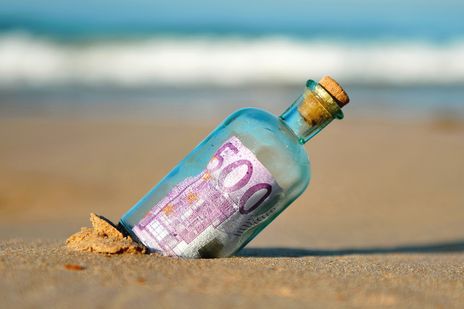 Eine Flaschenpost mit Geld im Sand