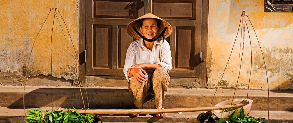 Vietnamesische Frau sitzt auf einer Treppe und lächelt