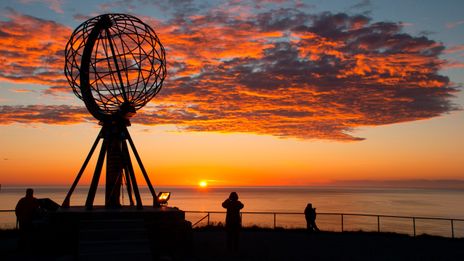 Sonnenuntergang am Nordkap mit dem bekannten Globus-Denkmal und Besuchern im Vordergrund