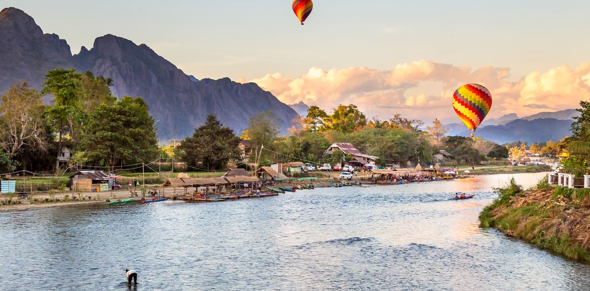Flusslandschaft bei Vang Vieng mit Bergen und bunten Heißluftballons