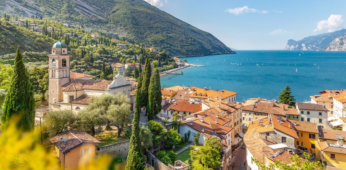 Blick auf Torbole am Gardasee mit Altstadt, Kirche, grünen Hügeln und Gardasee im Hintergrund