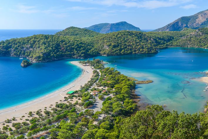 Türkisfarbene Lagune in Muğla mit Sandstrand, Landzunge und grünen Hügeln