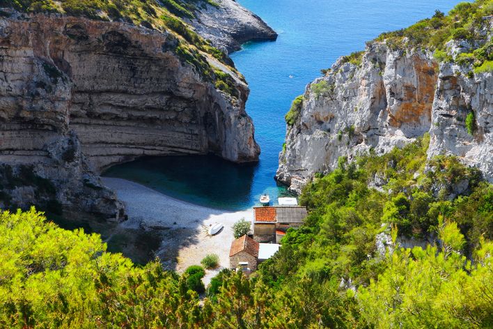 Blick auf den Stiniva-Strand auf der Insel Vis in Kroatien, umgeben von hohen Felsen und türkisblauem Wasser