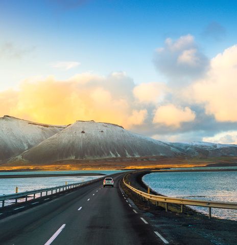 Auto fährt auf einer Straße durch die Landschaft Islands