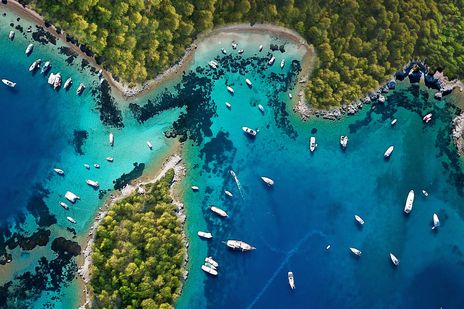 Luftaufnahme einer Bucht bei Bodrum mit Booten, türkisfarbenem Wasser und grüner Küste
