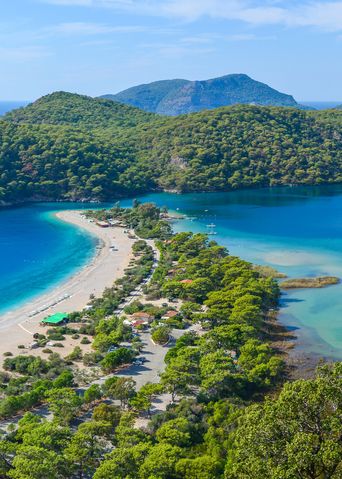 Türkisfarbene Lagune in Muğla mit Sandstrand, Landzunge und grünen Hügeln