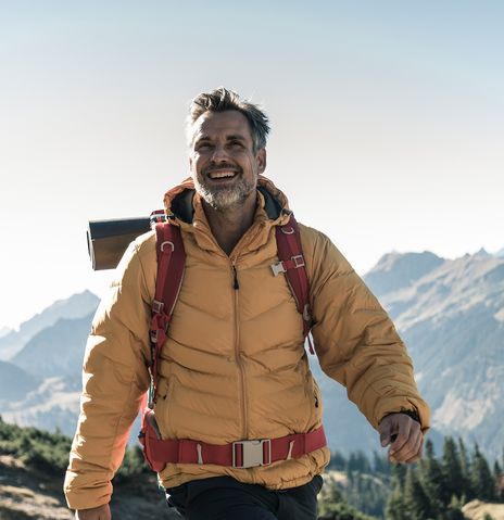 Mann mit einer gelben Jacke beim Wandern in den Bergen in Österreich