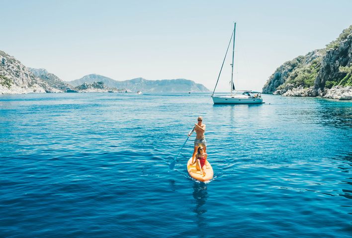 Paar auf einem Stand-up-Paddle in einer türkisblauen Bucht