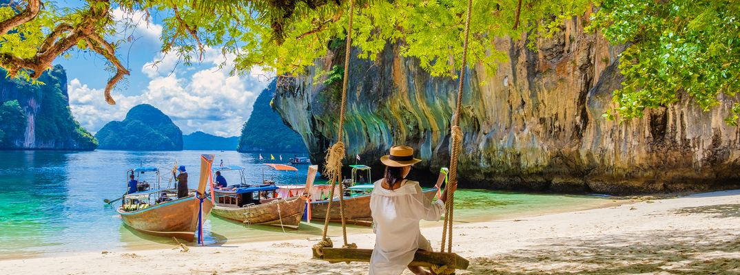Eine Frau sitzt auf einer Schaukel am Strand von Thailand