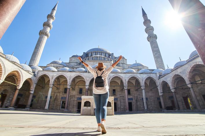 Frau steht im Innenhof einer Moschee in Istanbul mit Blick auf Kuppeln