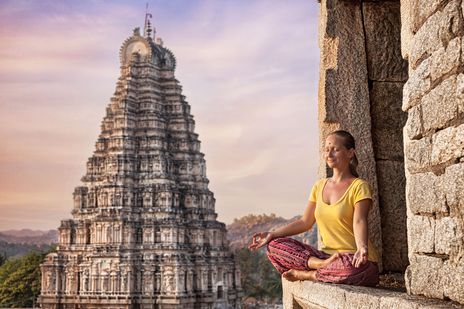 Frau im Schneidersitz vor einem Tempel in Indien