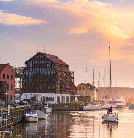 Hafen von Klaipėda bei Sonnenuntergang mit historischen Speichern und Booten