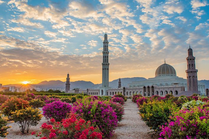 Moschee in Maskat mit Minaretten, Blumenbeeten und dramatischem Himmel