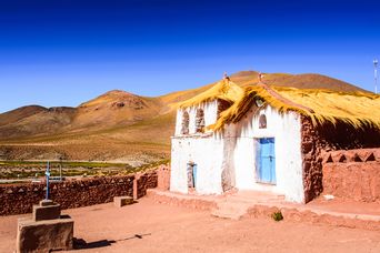 Lehmhaus in San Pedro de Atacama vor trockener Wüstenlandschaft