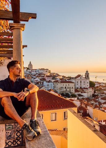 Mann genießt bei einem Sonnenuntergang den Blick auf die Stadt Lissabon