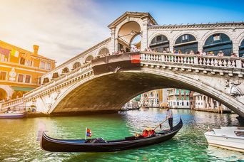 Die majestätische Rialto Brücke über dem Canal Grande in Venedig mit einer Gondel im Vordergrund, Italien