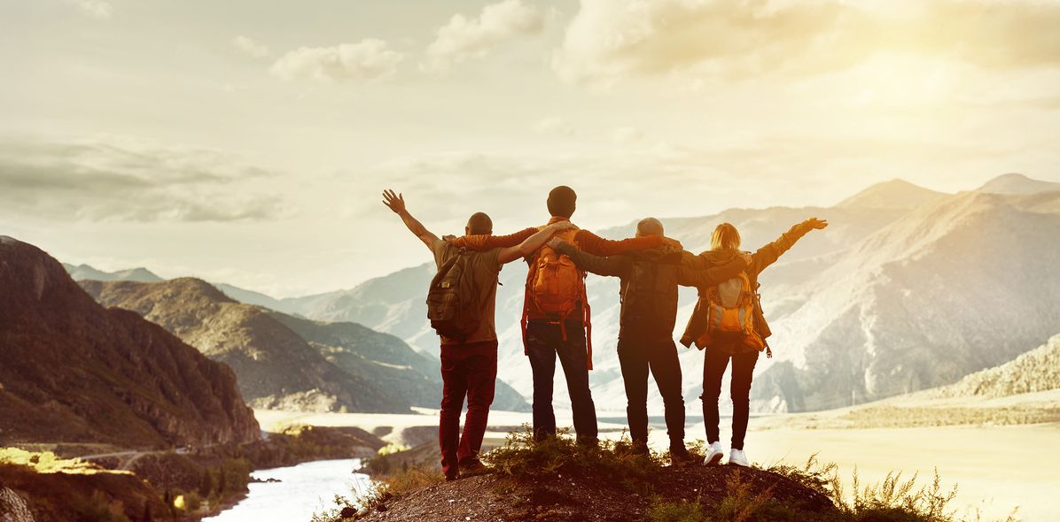 Vier Personen stehen gemeinsam auf einem Berg mit Ausblick auf die Landschaft