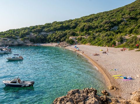 Strand auf der Insel Cres in Kroatien mit Kies, glasklarem Wasser und grüner Natur im Hintergrund