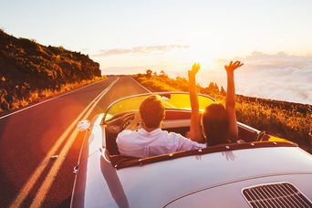 Ein Paar fährt in den Sonnenuntergang mit dem Mietwagen