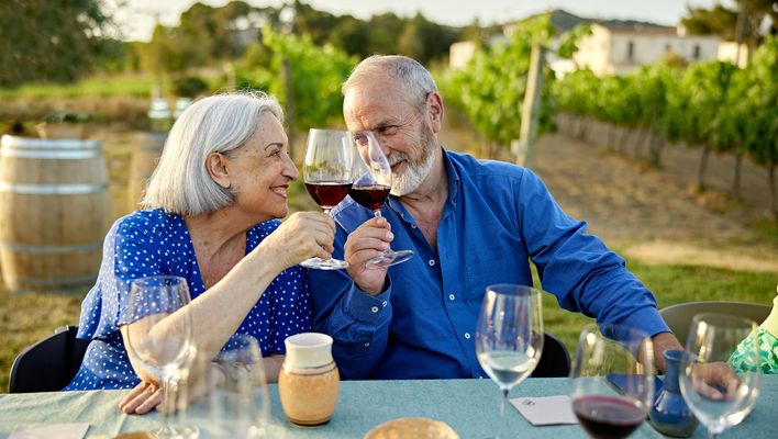 Älteres glückliches Paar gemeinsam bei einer Weinprobe in den Weinbergen