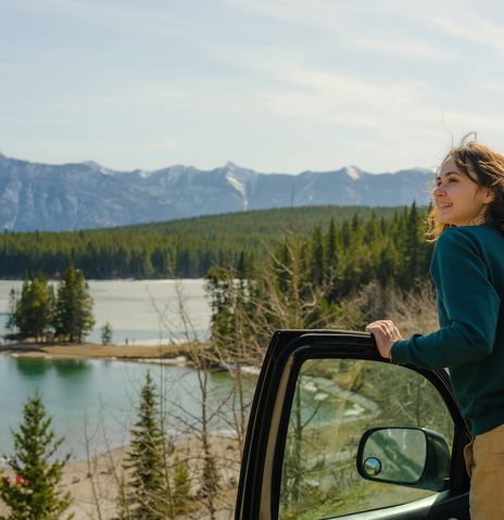 Frau steigt aus ihrem Auto aus und blickt auf die Landschaft im Banff Nationalpark, Kanada