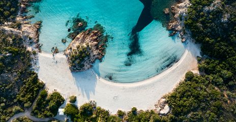 Luftaufnahme von einem Strand auf Sardinien mit weißem Sand und türkisfarbenem Wasser