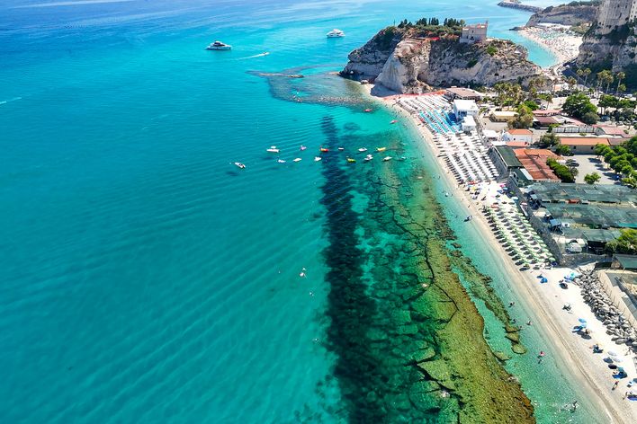 Blick aus der Luft auf den Strand von Tropea mit seinem kristallklaren Wasser und der Promenade, Kalabrien, Italien
