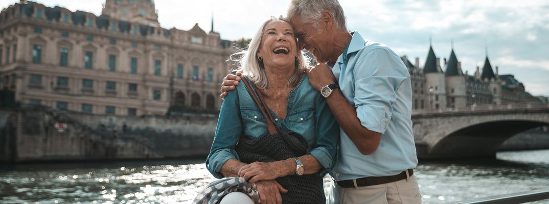 Paar sitzt an der Seine in Paris mit Blick auf historische Gebäude