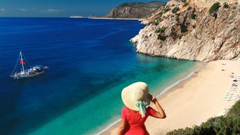 Frau mit Sonnenhut blickt auf eine Bucht an der türkischen Küste