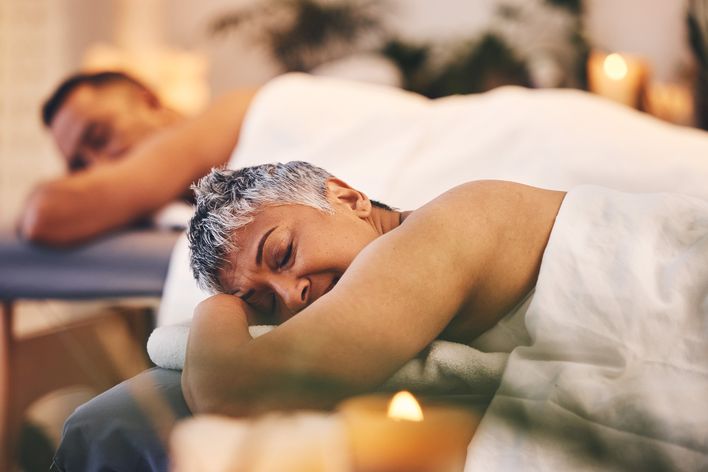 Frau erhält entspannende Massage bei Kerzenschein in einem Wellnessbereich