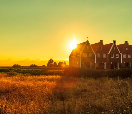 Abendstimmung in den Niederlanden mit Windmühle, Häuserreihe und weitem Feld im Sonnenuntergang