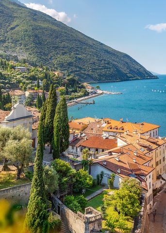 Blick auf Torbole am Gardasee mit Altstadt, Kirche, grünen Hügeln und Gardasee im Hintergrund