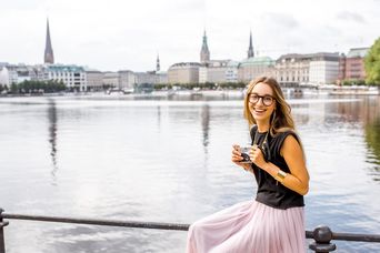 Frau sitzt an der Alster und macht Fotos in Hamburg