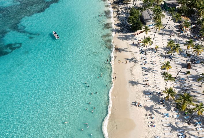 Blick auf türkisblauen Karibikstrand mit Palmen und weißem Sand