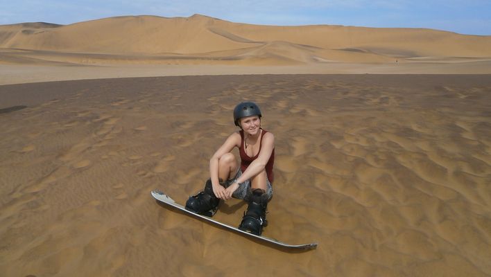 Mitarbeiterin Dana beim Sandborden in den Dünen von Namibia