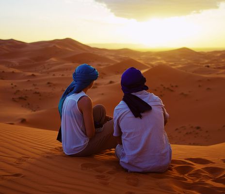 Ein Paar sitzt auf einer Düne während des Sonnenuntergangs