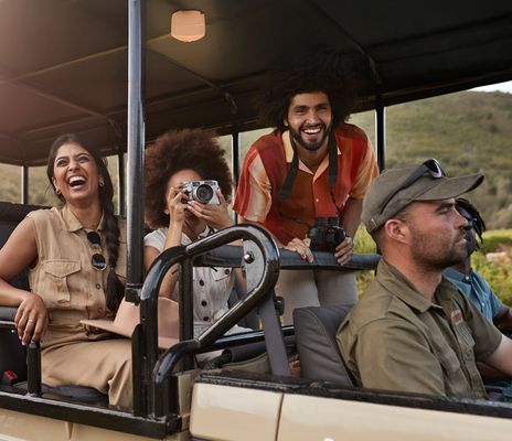 Eine kleine, lachende Reisegruppe im 4x4 Geländewagen auf Safari in Südafrika 