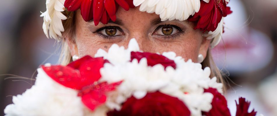 Frau mit Blumenkranz versteckt hinter Blumen