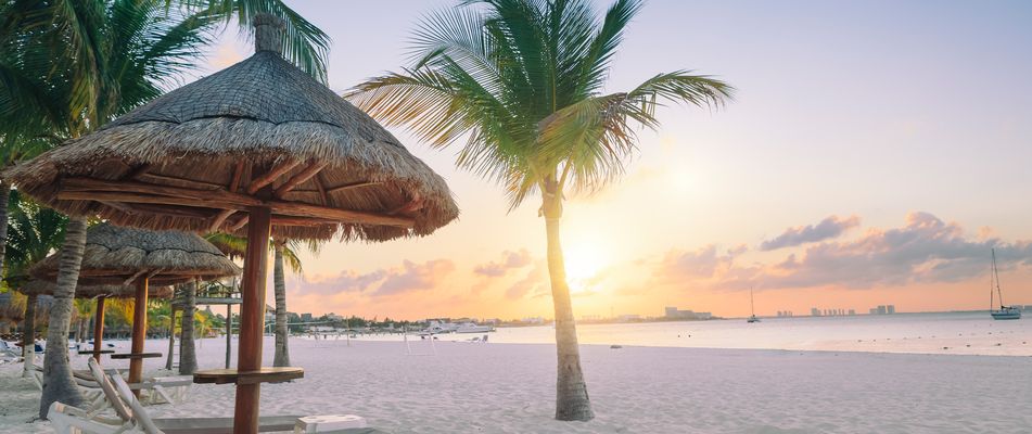 Strand bei Cancún mit Palmen und Sonnenuntergang über dem Meer