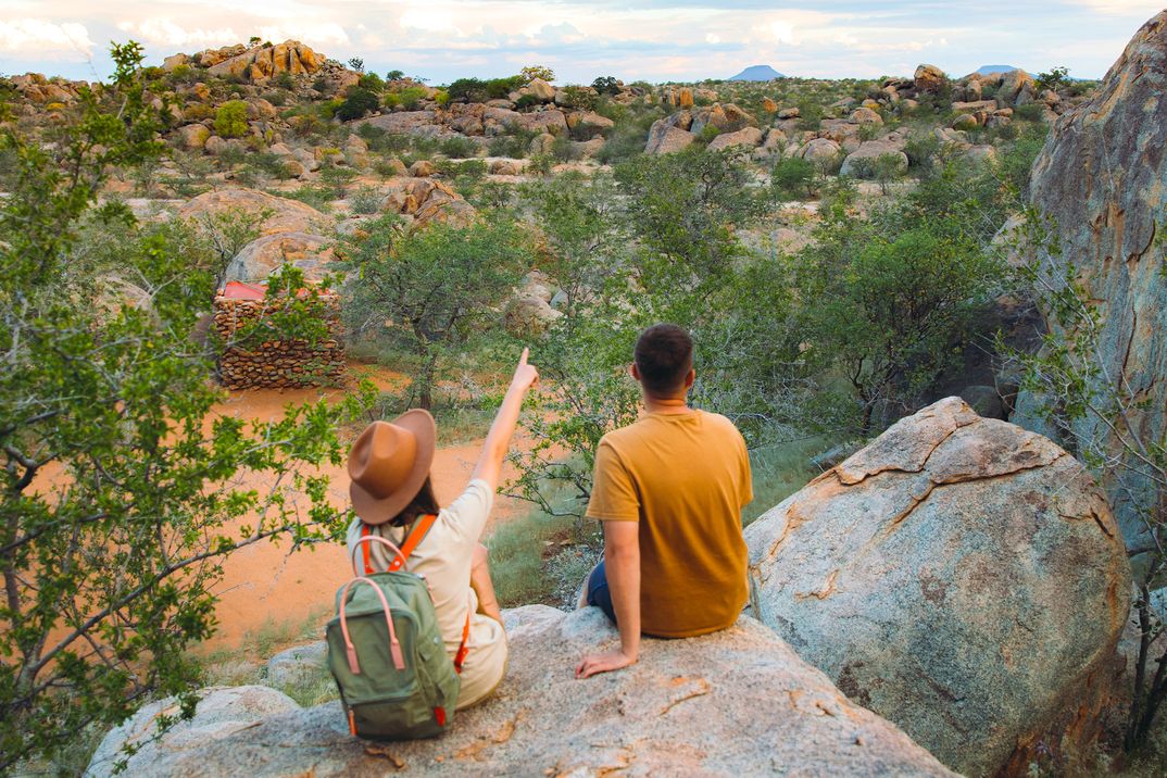 Ein Paar sitzt auf einem Felsen in der wüste Namib und beobachtet die Gegend