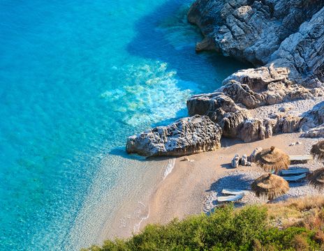  Der malerische Strand von Himare an der albanischen Riviera mit türkisfarbenem Wasser und Sonnenschirmen