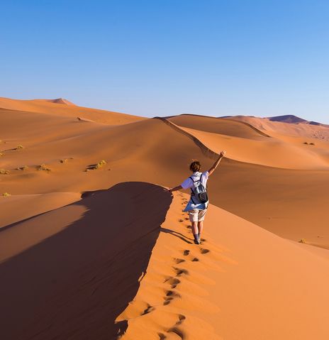 Eine Frau spaziert auf den Sossusvlei Dünen