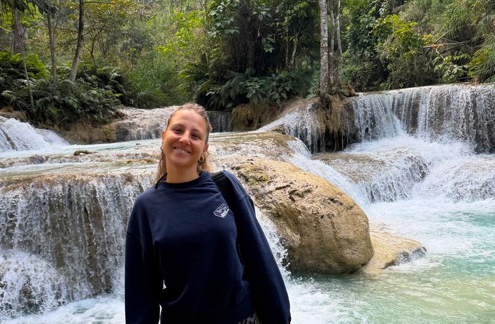 Mitarbeiterin Julia unterwegs in Laos vor einem Wasserfall