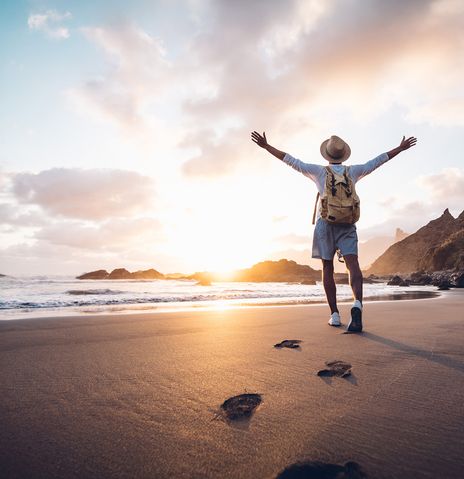 Mann mit Hut läuft am Strand