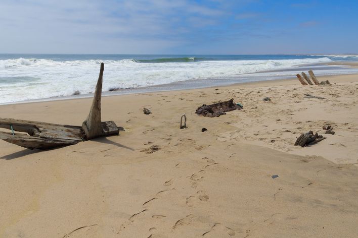 Einsamer Sandstrand mit Schiffswrack an der rauen Skelettküste Namibias