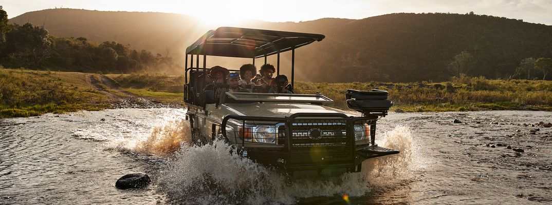 Gruppe fährt mit Allrad durch Wasser während einer Safari