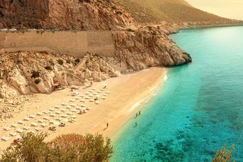 Die helle Sandbucht KAPUTAŞ BEACH an der türkischen Riviera mit klarem Wasser und felsiger Küstenlandschaft