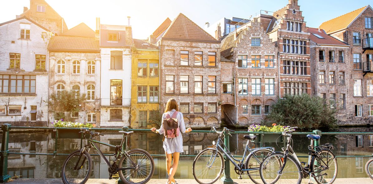 Frau mit Fahrrad vor historischen Häusern in Gent, Belgien
