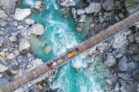 Menschen liegen auf einer Brücke darunter fließt der Triglav von Slowenien
