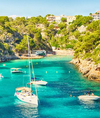 Felsige Bucht auf Mallorca mit Segelbooten und glasklarem Meer im Sommer